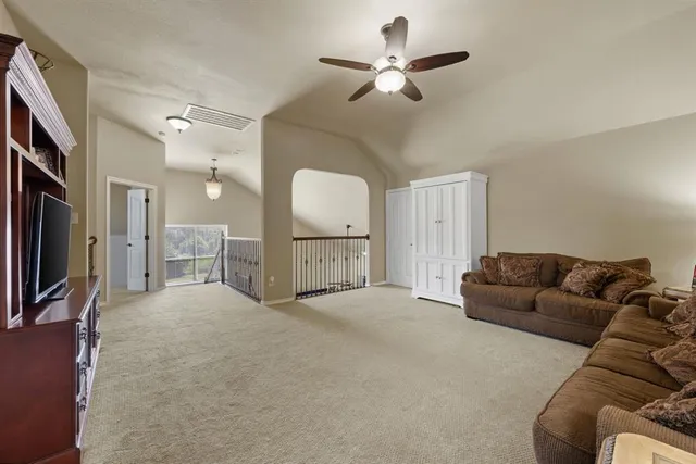 a living room with furniture a flat screen tv and a refrigerator