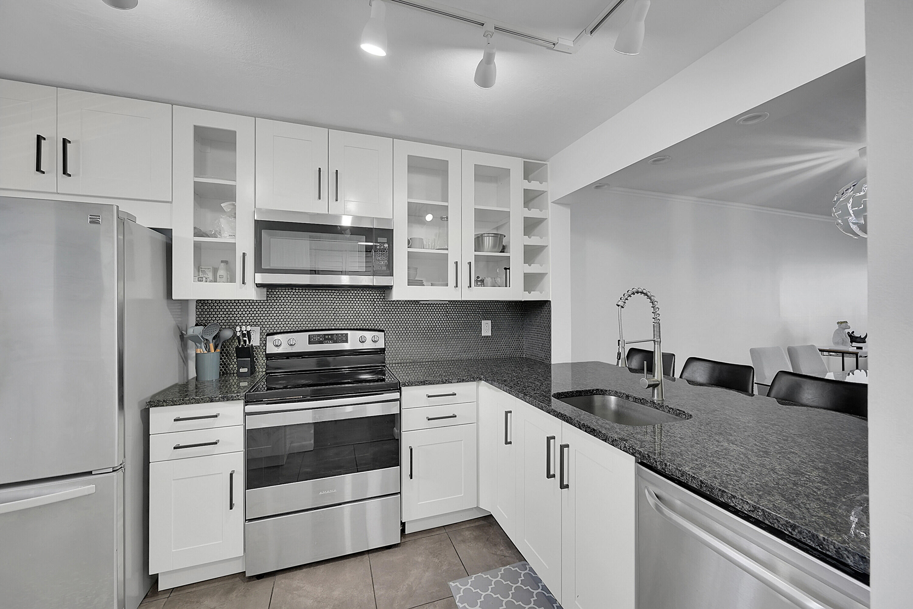 2920 Southwest 22nd Avenue, Unit 6040 Delray Beach, FL 33445 - Photo 24 of 53 a kitchen with granite countertop a sink stainless steel appliances and white cabinets