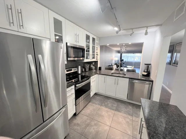 a large kitchen with a refrigerator a sink a stove top oven and cabinets