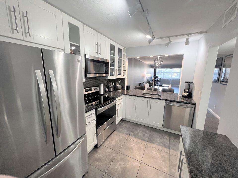 2920 Southwest 22nd Avenue, Unit 6040 Delray Beach, FL 33445 - Photo 3 of 53 a large kitchen with a refrigerator a sink a stove top oven and cabinets