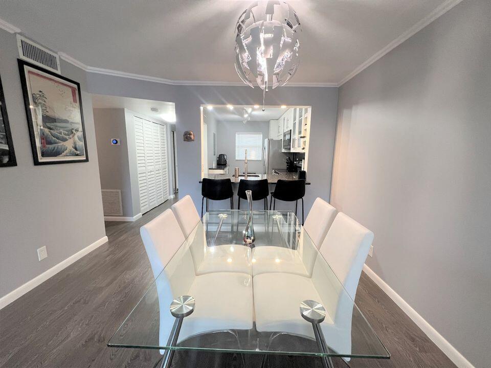 2920 Southwest 22nd Avenue, Unit 6040 Delray Beach, FL 33445 - Photo 6 of 53 a view of a dining room with furniture a chandelier and wooden floor