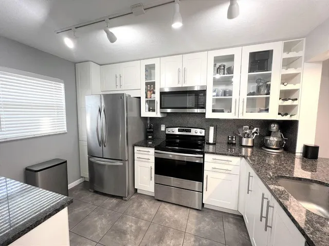 a kitchen with stainless steel appliances granite countertop a stove a sink and a refrigerator