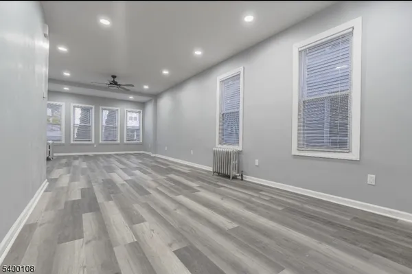 a view of empty room with wooden floor and fan
