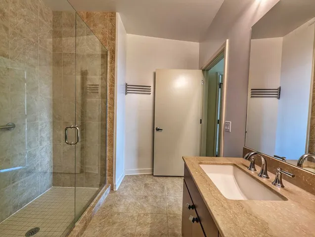 a bathroom with a granite countertop shower sink and mirror