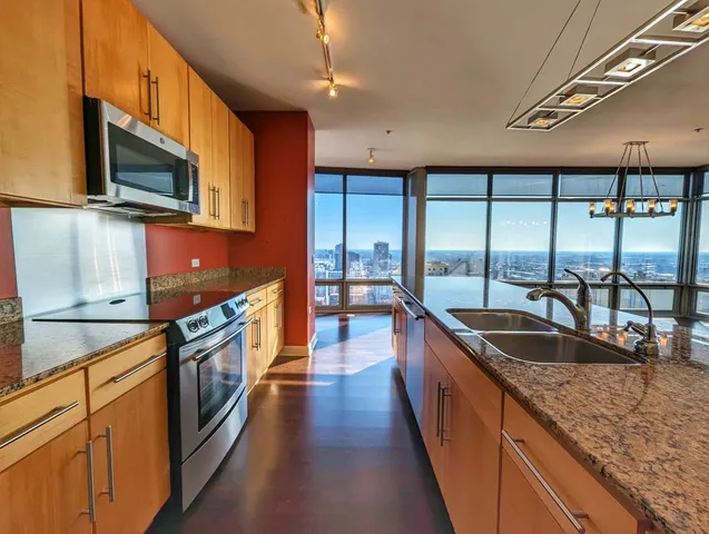 a kitchen with stainless steel appliances granite countertop a sink a stove and a wooden floors