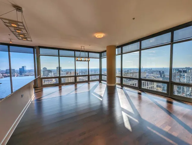 a view of an empty room with wooden floor and a floor to ceiling window