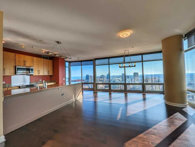a view of a kitchen with kitchen island a counter top space a sink a refrigerator and a view of living room