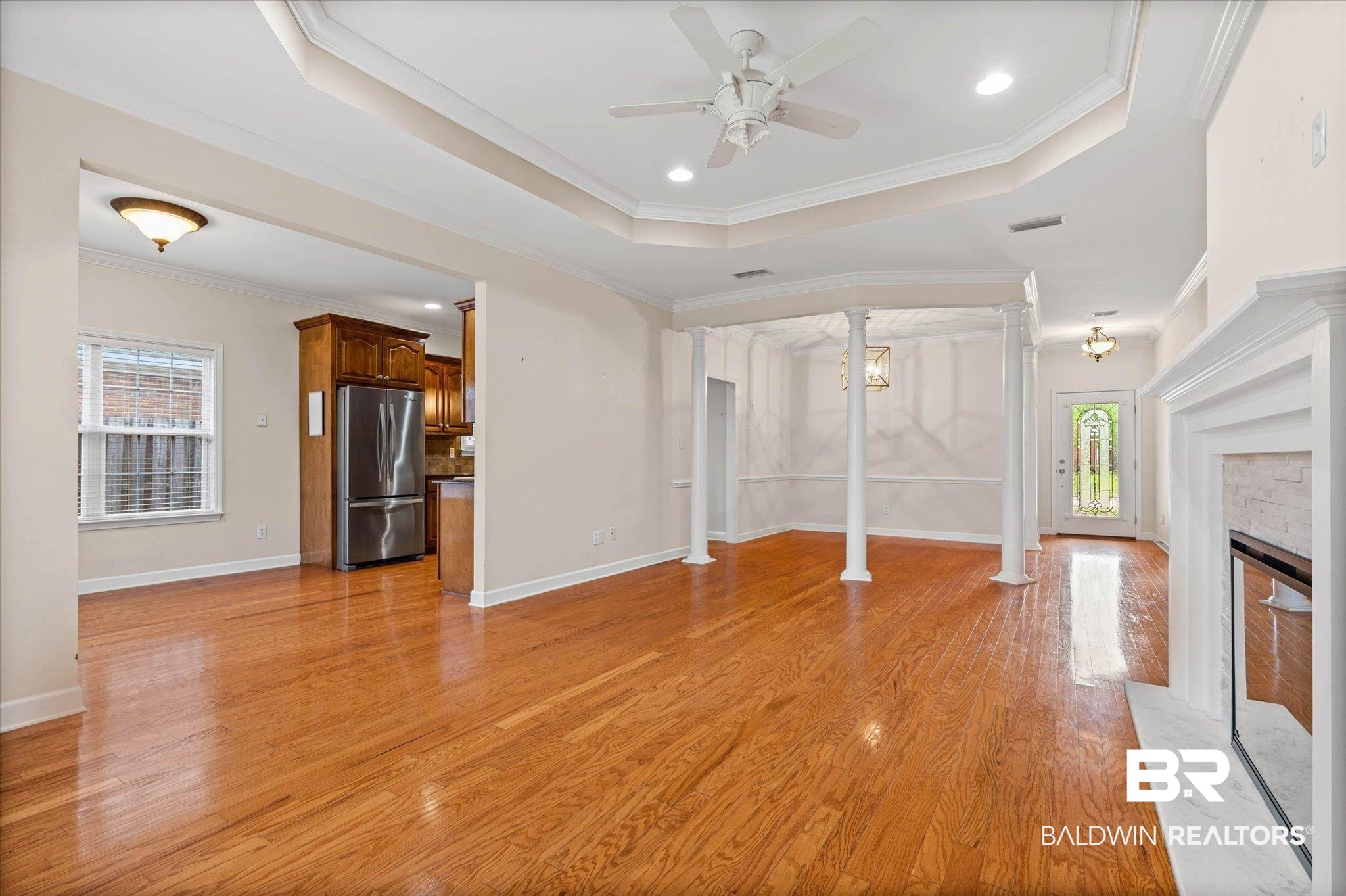 1003 Weatherby Street South Saraland, AL 36571 - Photo 11 of 31 Unfurnished living room featuring healthy amount of natural light, a raised ceiling, decorative columns, crown molding, and recessed lighting