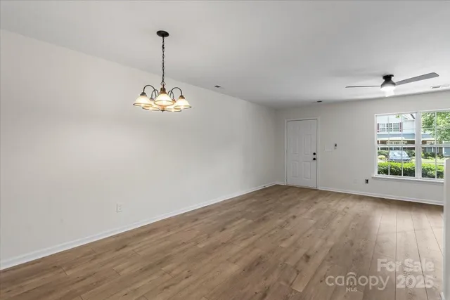 a view of a room with wooden floor chandelier and windows
