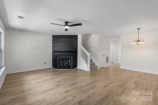 a view of an empty room with wooden floor fireplace and a window