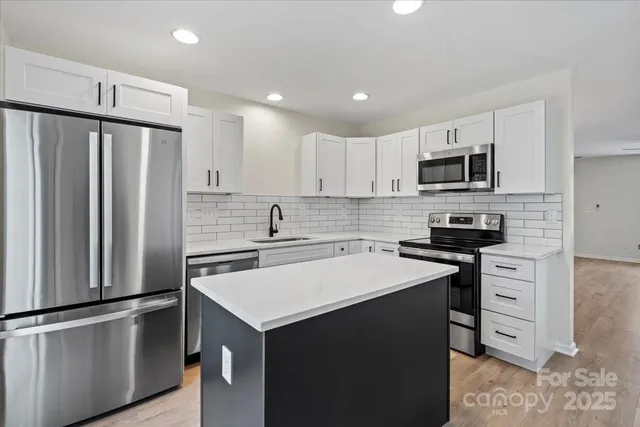 a kitchen with kitchen island a sink appliances and cabinets