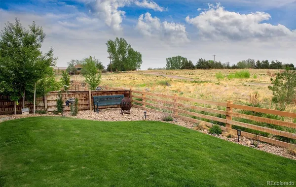 a view of a lake with a big yard with table and chairs and wooden fence