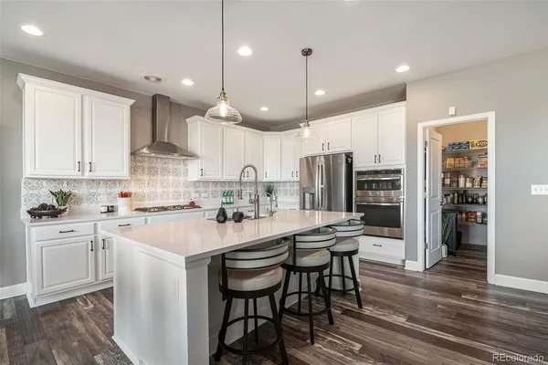 a kitchen with stainless steel appliances kitchen island granite countertop a wooden floor and white cabinets