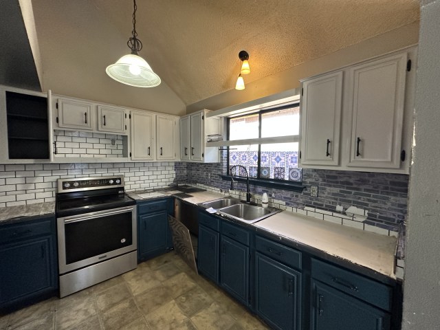 548 Spring River Drive Martindale, TX 78655 - Photo 11 of 17 Kitchen featuring two tone cabinets, electric stove, decorative light fixtures, lofted ceiling, and tasteful backsplash