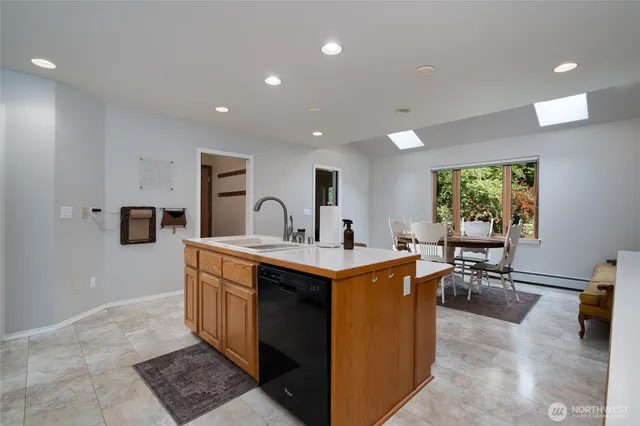 a view of kitchen with stainless steel appliances granite countertop dining table chairs sink and white cabinets