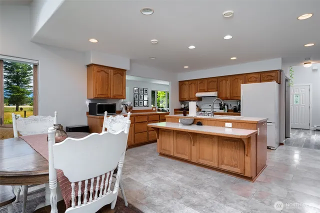 a kitchen with stainless steel appliances kitchen island granite countertop a sink and a refrigerator