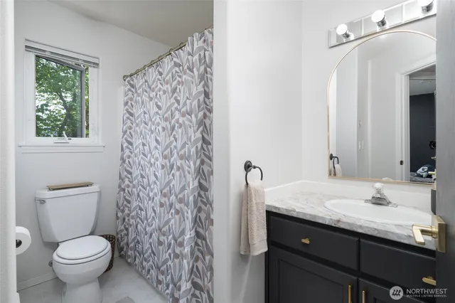 a bathroom with a granite countertop sink toilet and mirror