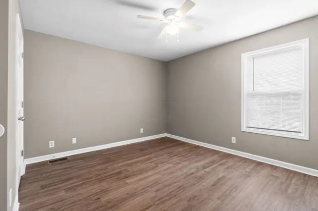 an empty room with wooden floor and windows