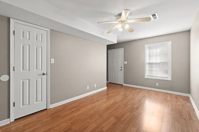 a view of an empty room with wooden floor and a window
