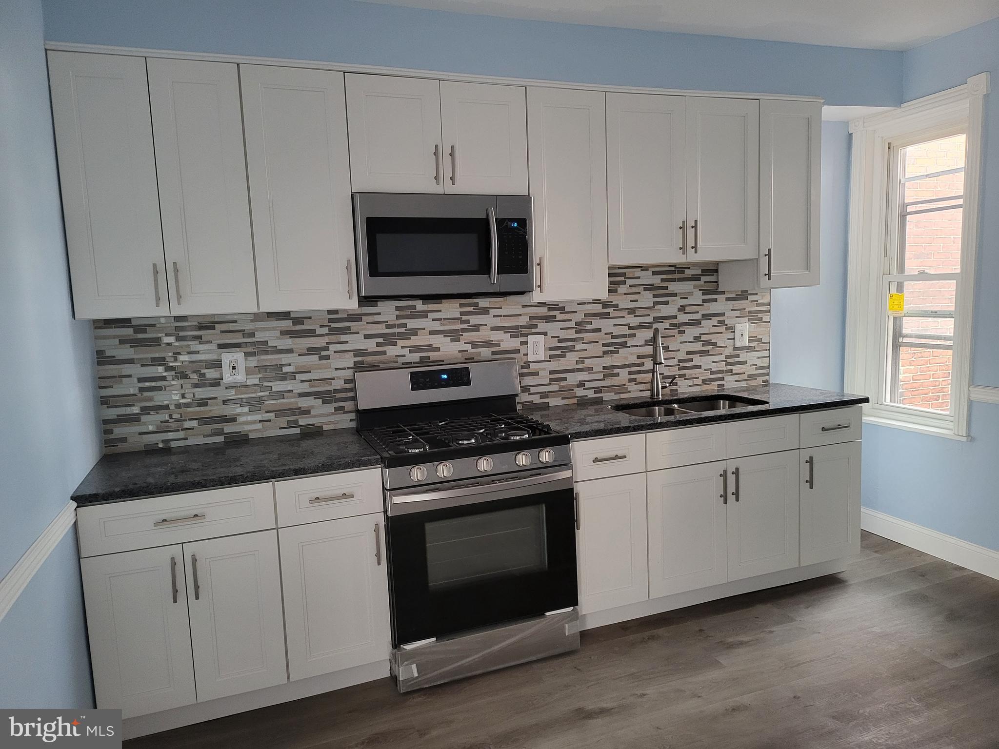 1817 Mifflin Street Philadelphia, PA 19145 - Photo 16 of 16 a kitchen with stainless steel appliances granite countertop white cabinets granite counter tops and a hard wood floors