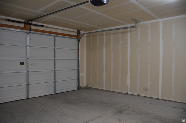 1842 South 1280th Street West Logan, UT 84321 - Photo 19 of 21 Garage interior featuring a sectional overhead door, concrete flooring, and unfinished drywall walls