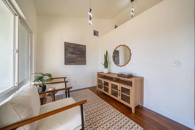 a living room with stainless steel appliances granite countertop furniture wooden floor and a window
