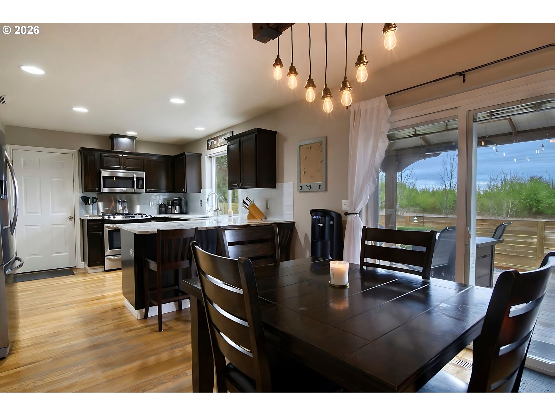 59016 Timberline Avenue St. Helens, OR 97051 - Photo 12 of 36 a kitchen with stainless steel appliances kitchen island granite countertop a table chairs and a refrigerator