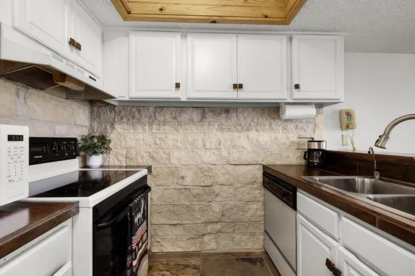 a kitchen with granite countertop white cabinets and sink