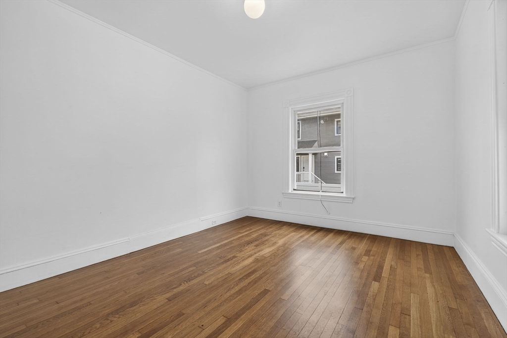 168 Elliot Street, Unit 1 Newton, MA 02464 - Photo 11 of 15 a view of an empty room with wooden floor and a window