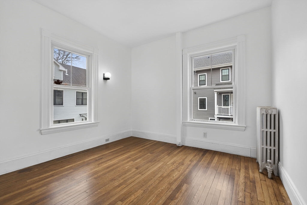 168 Elliot Street, Unit 1 Newton, MA 02464 - Photo 6 of 15 a view of an empty room with a window and wooden floor