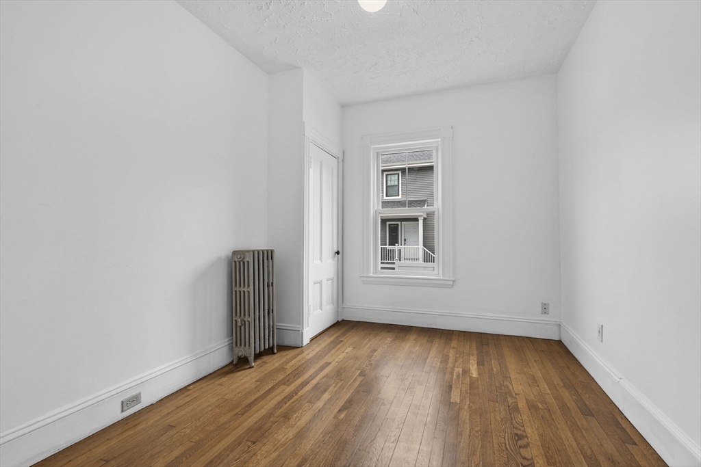 168 Elliot Street, Unit 1 Newton, MA 02464 - Photo 9 of 15 an empty room with wooden floor and windows