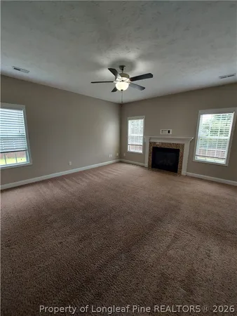an empty room with windows and fireplace