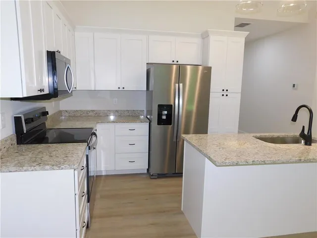 a kitchen with granite countertop a sink stove and refrigerator
