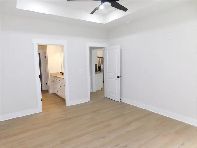 an empty room with wooden floor and ceiling fan
