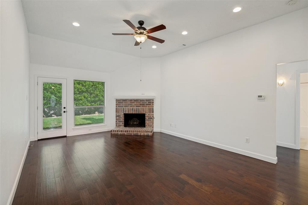 8160 Tower Road Frisco, TX 75035 - Photo 13 of 25 an empty room with wooden floor a ceiling fan and a fireplace