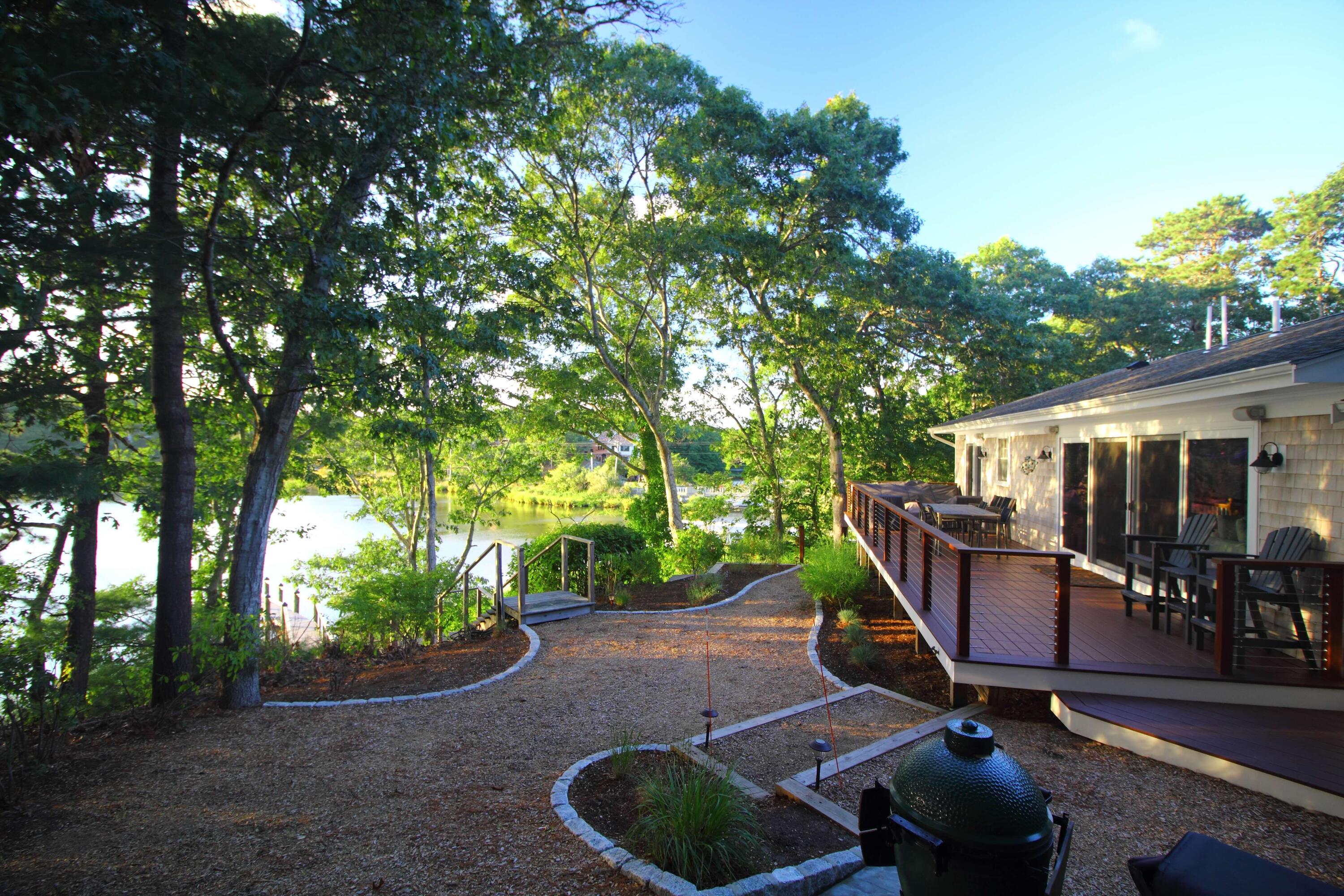 24 Bay Road Cotuit, MA 02635 - Photo 2 of 44 a view of a patio with table and chairs potted plants and large tree