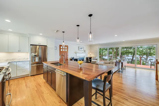 a kitchen with stainless steel appliances granite countertop a stove top oven a refrigerator a sink and dining table with wooden floor