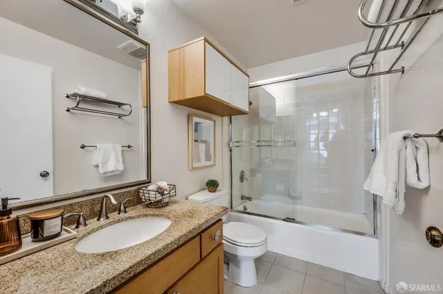 a bathroom with a granite countertop sink a toilet and shower