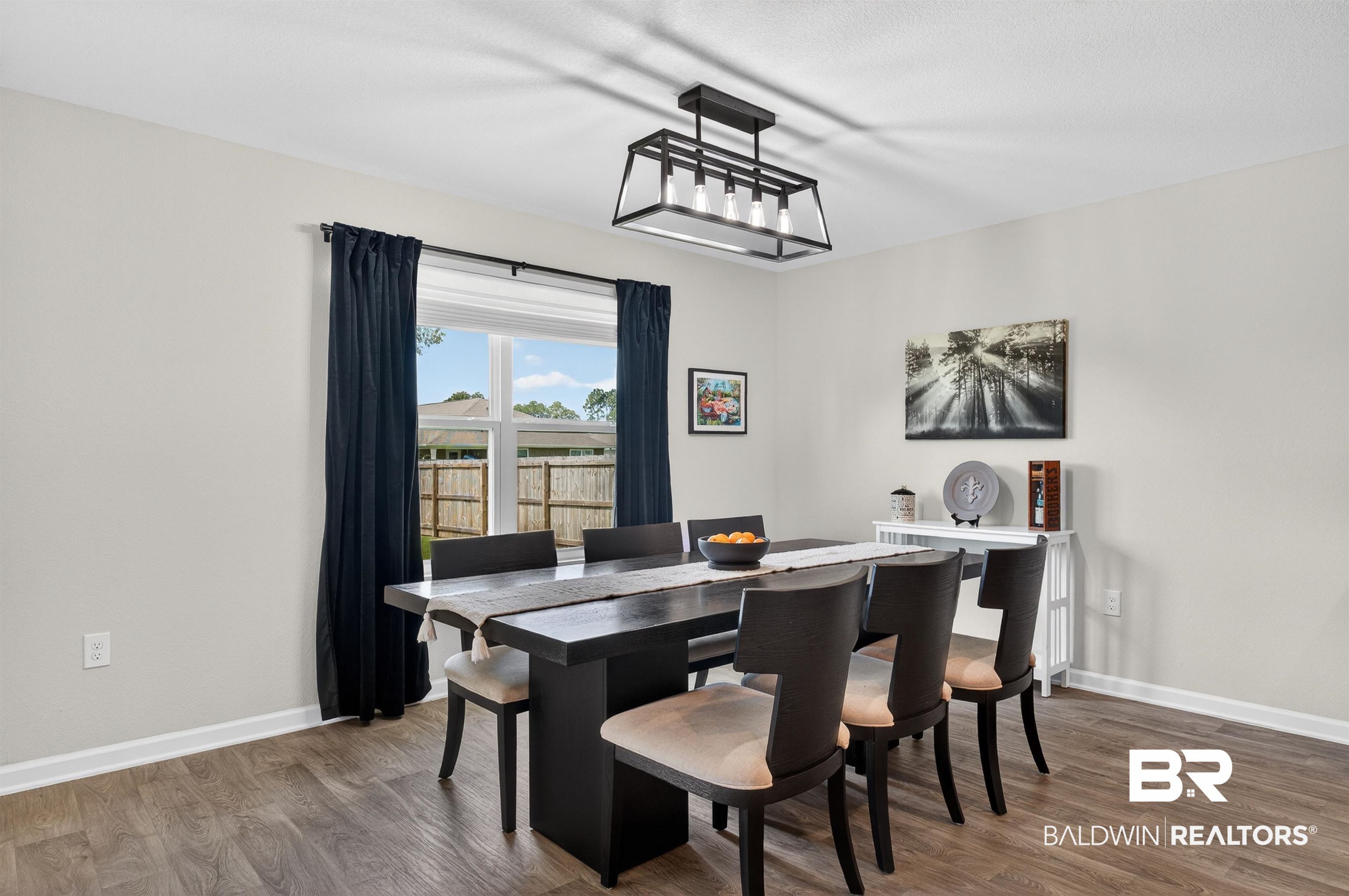 3213 Camino Real Loop Lillian, AL 36549 - Photo 26 of 61 Bright interior space with wood-finish flooring, a contemporary linear chandelier, and a large window