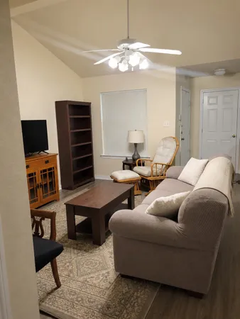 a living room with furniture a flat screen tv and kitchen view