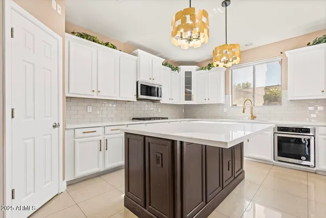 a large kitchen with kitchen island granite countertop a large window and white cabinets