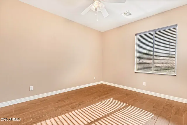 a view of an empty room with window and chandelier fan