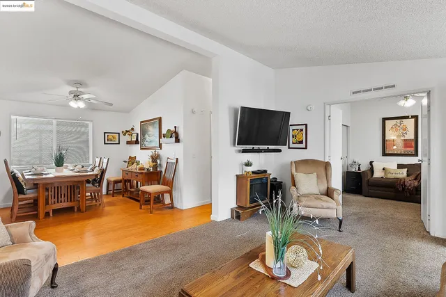 a living room with furniture a flat screen tv and kitchen view