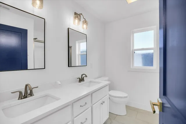 a bathroom with a toilet a sink a mirror and vanity