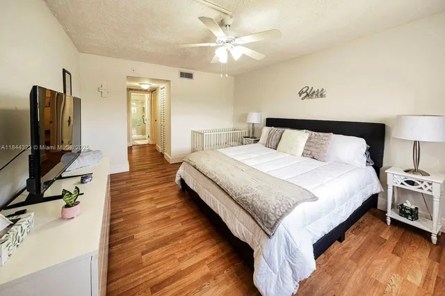 a spacious bedroom with a bed and a flat tv screen on a dresser