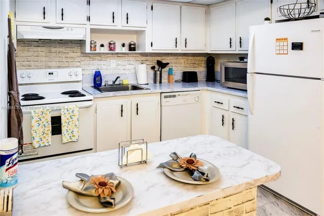 a kitchen with stainless steel appliances kitchen island granite countertop a stove and white cabinets