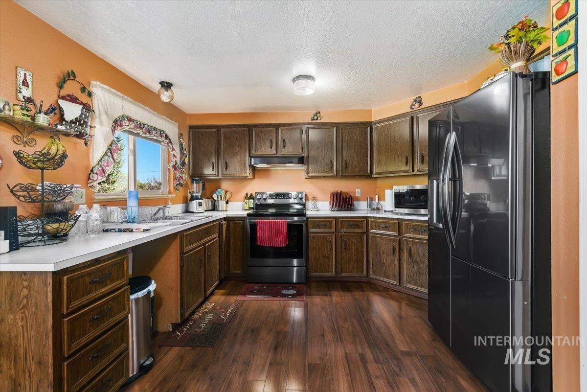 2811 Apollo Place Caldwell, ID 83605 - Photo 9 of 31 Kitchen with stainless steel appliances, dark wood finish cabinets, dark wood-style flooring, light countertops, and a textured ceiling