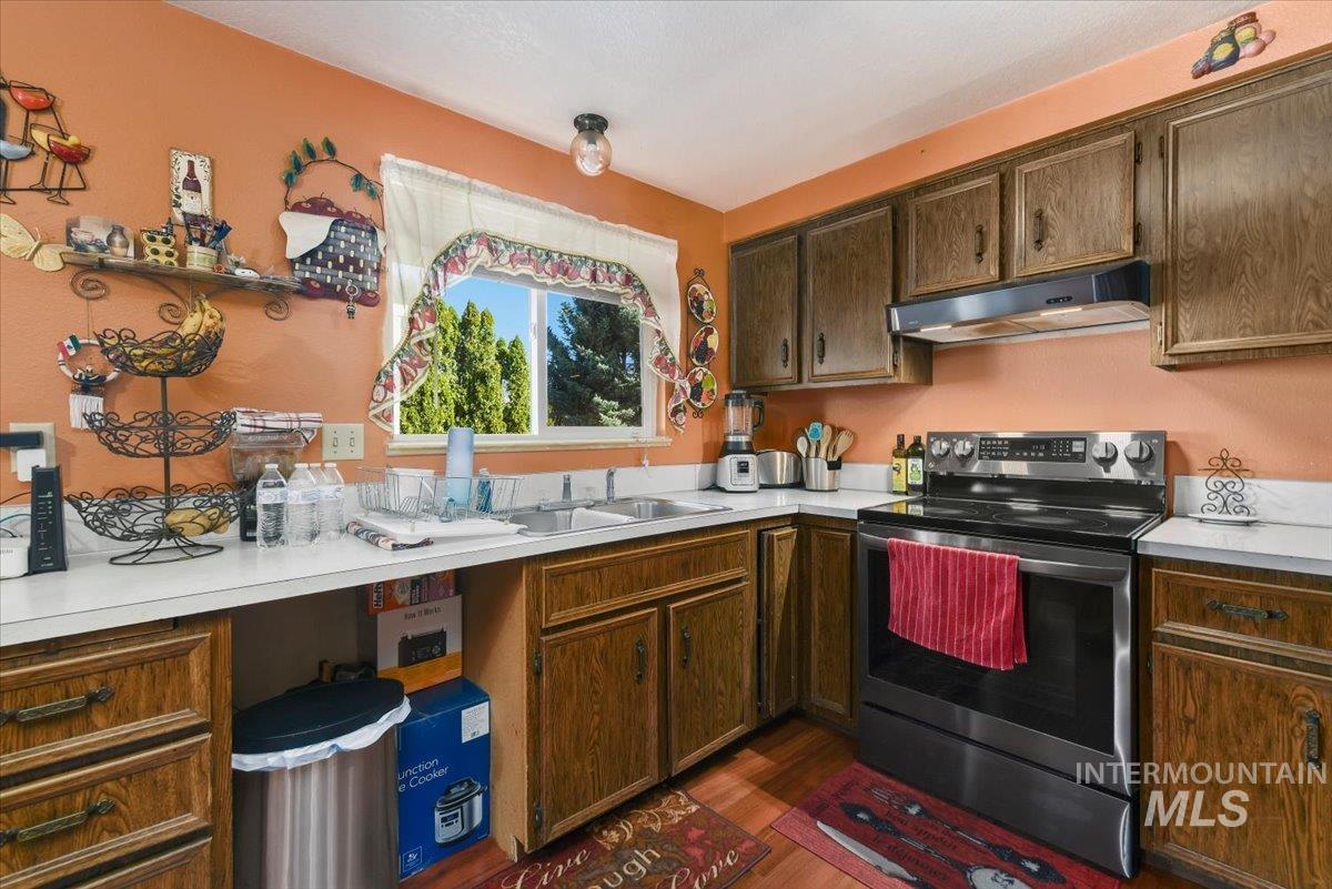 2811 Apollo Place Caldwell, ID 83605 - Photo 10 of 31 Kitchen featuring stainless steel electric stove, light countertops, dark wood finished floors, and dark wood finish cabinets
