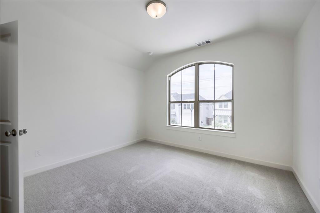 11548 Wulstone Road Haslet, TX 76052 - Photo 17 of 26 Room featuring an arched window, vaulted ceiling, neutral wall paint, and gray carpeting