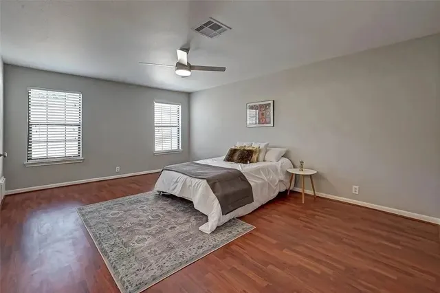 a spacious bedroom with a bed and wooden floor